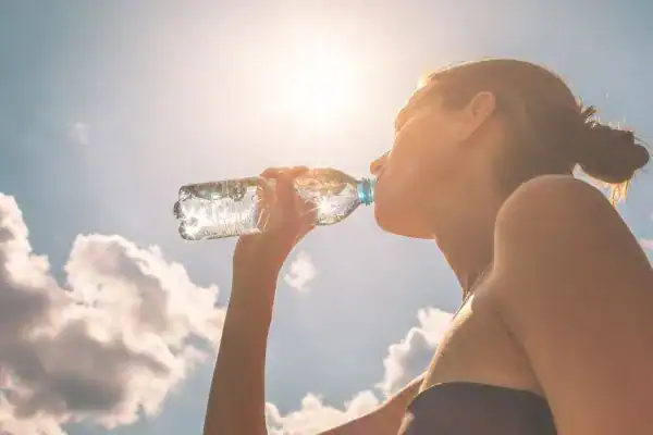 Hydration: The Secret Ingredient for a Toned Stomach and Enhanced Fitness 3 Image of woman drinking water to hydrate Oxted after run.