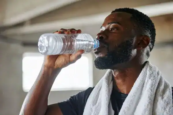 Hydration: The Secret Ingredient for a Toned Stomach and Enhanced Fitness 1 Image of man drinking water to improve hydration Oxted after work out.